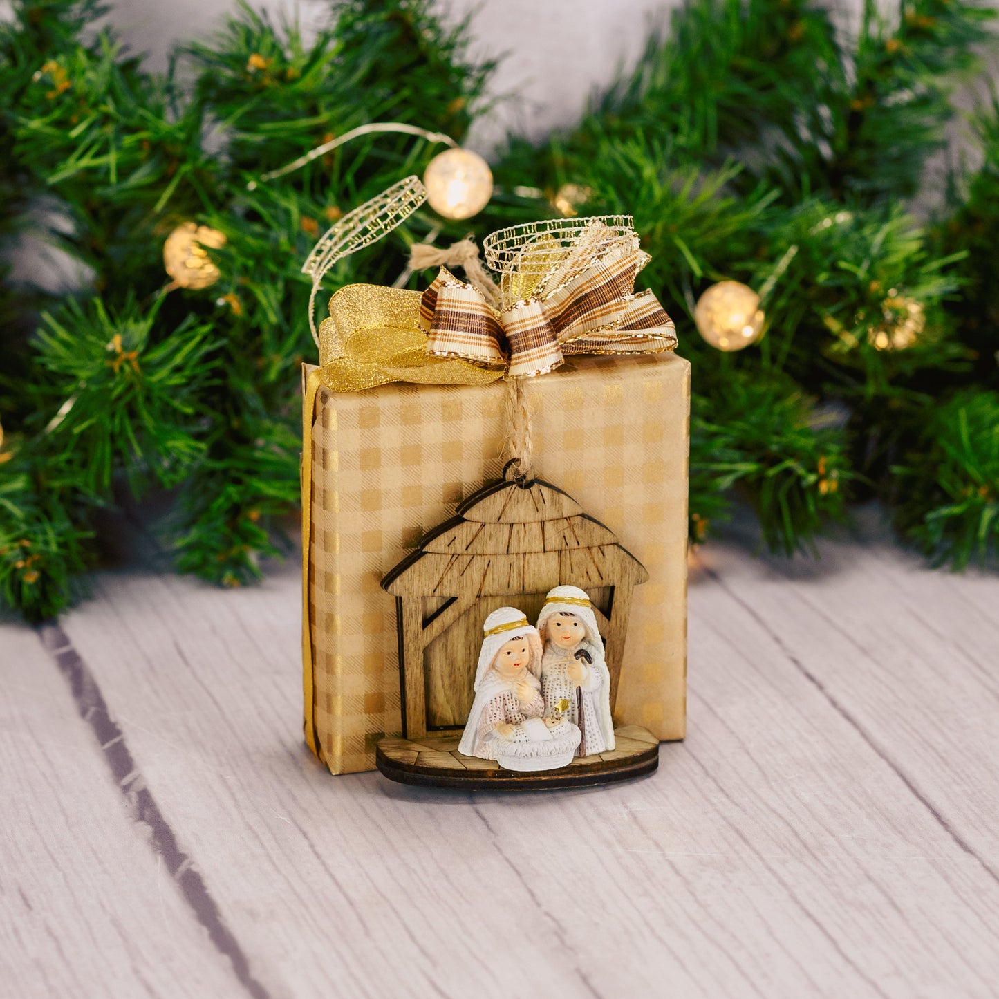 a sampler box of assorted chocolates is wrapped and tied with a wooden nativity ornament.