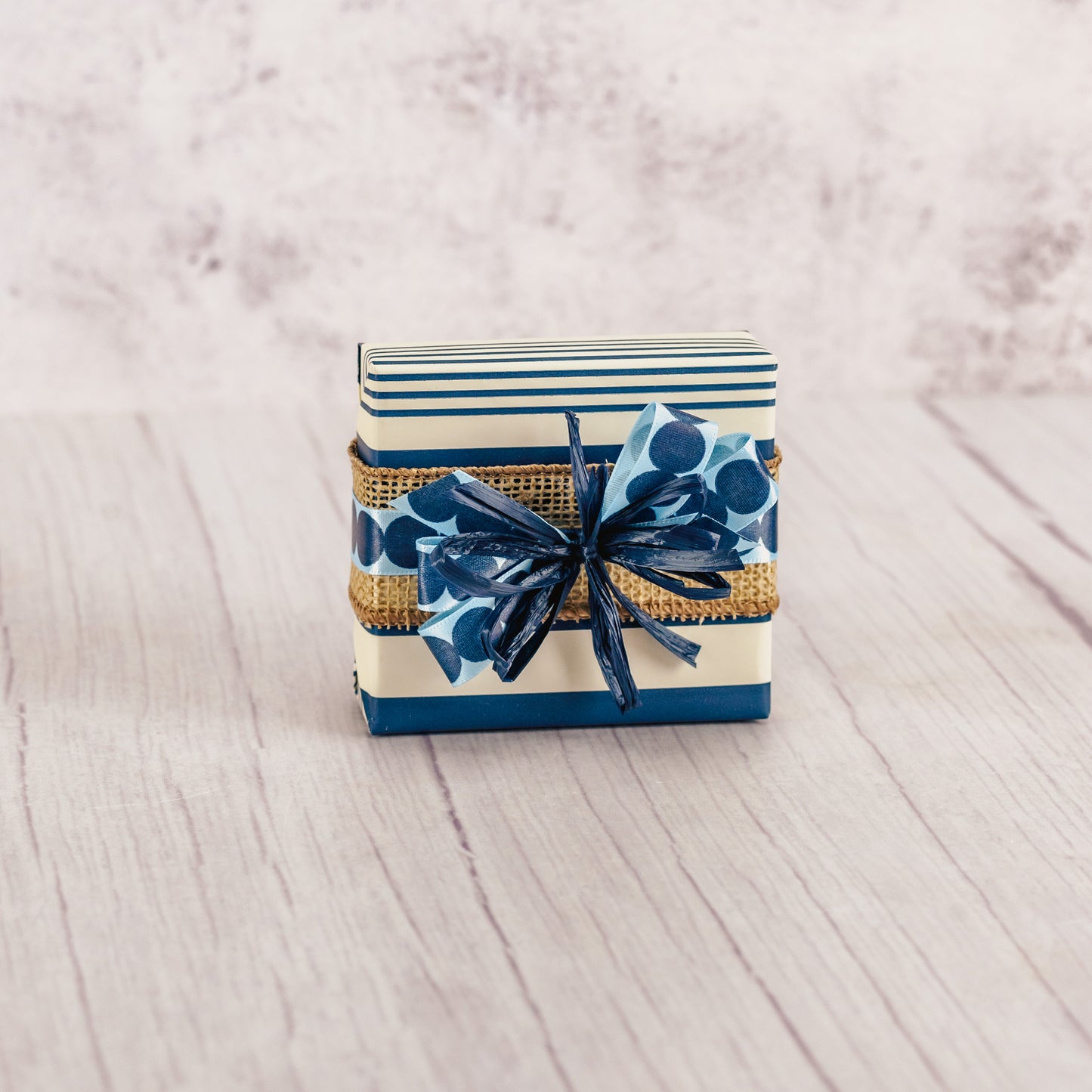 a sampler box of assorted chocolates wrapped in navy and white striped paper and tied with a handmade bow.