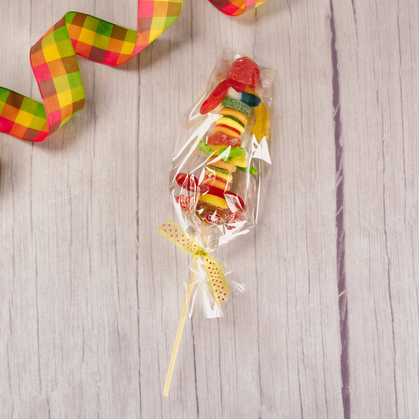 a kebob of assorted gummi pieces like: fruit slices, frogs, worms, cherries and more!