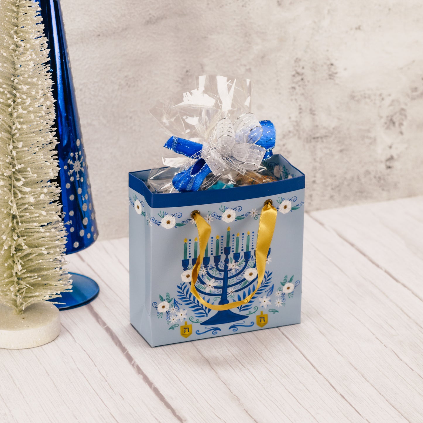 Gift bag with Menorah design filled with sweet treats for Hanukkah.