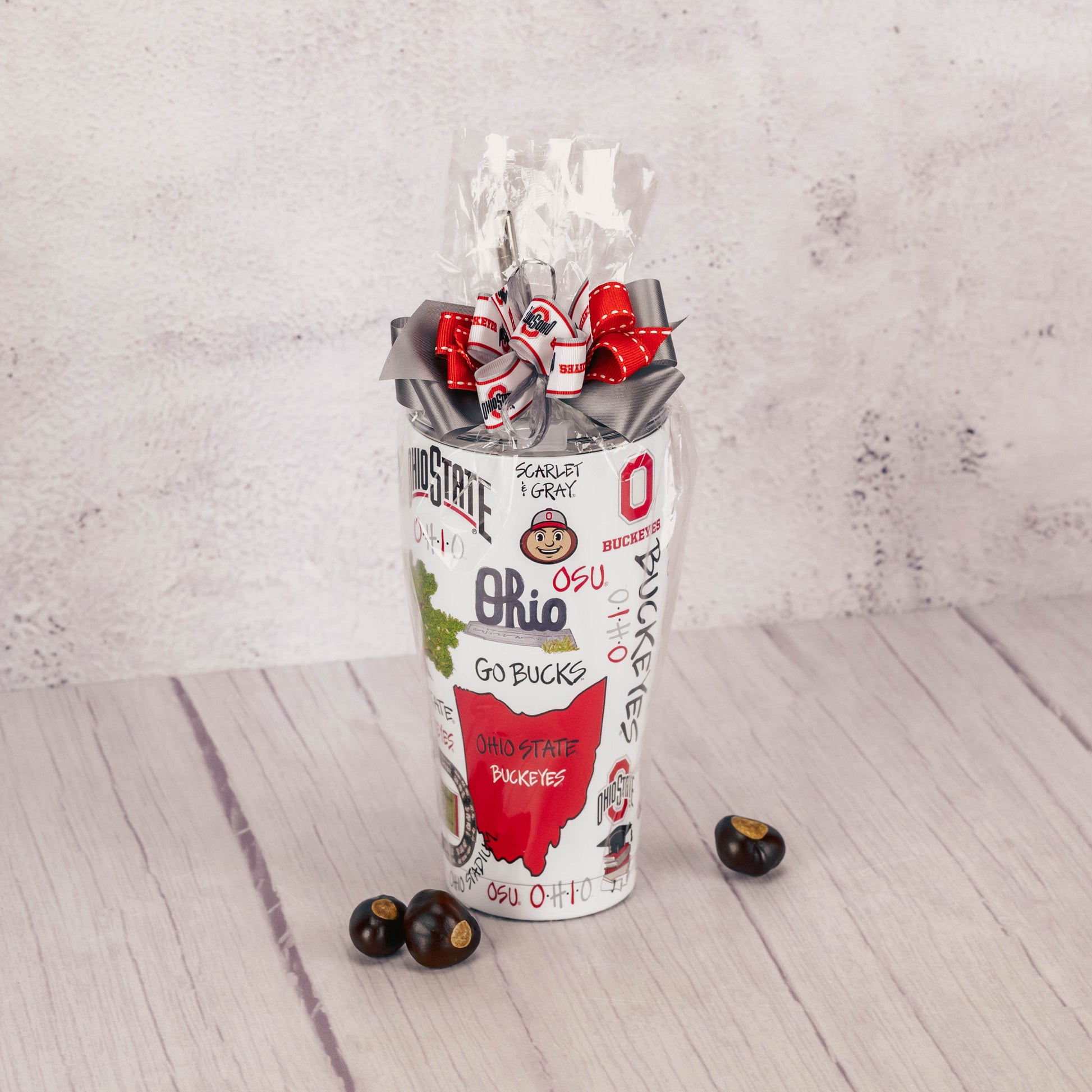 a large tumbler with straw that can hold 30 oz. of liquid is decorated with Ohio State icons and is filled with sweet treats.