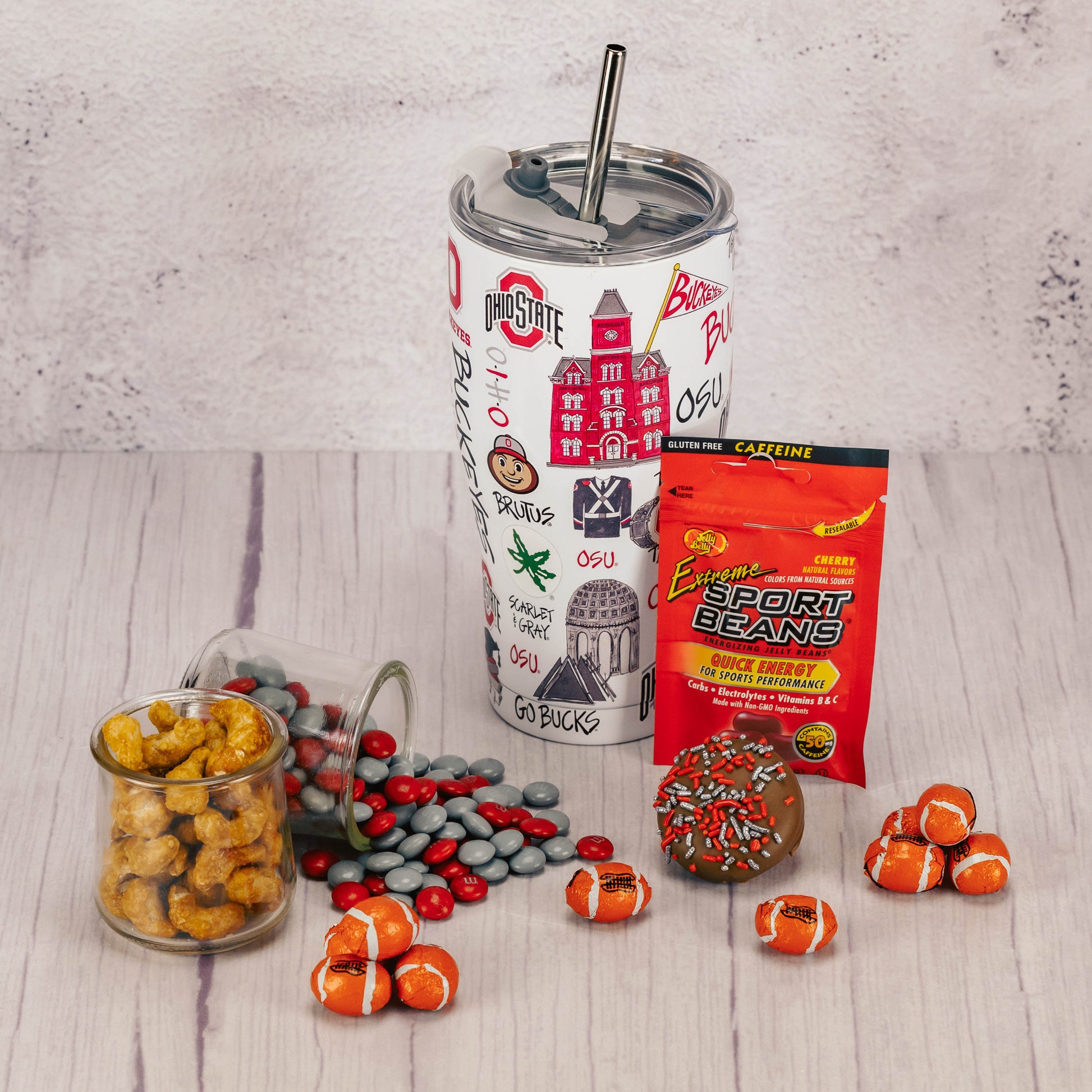 a large tumbler with straw that can hold 30 oz. of liquid is decorated with Ohio State icons and is filled with sweet treats.