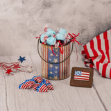  a patriotic graham cracker, raspberry taffy and milk chocolate american foil hearts are stuffed inside a metal pail decorated with stars and stripes.
