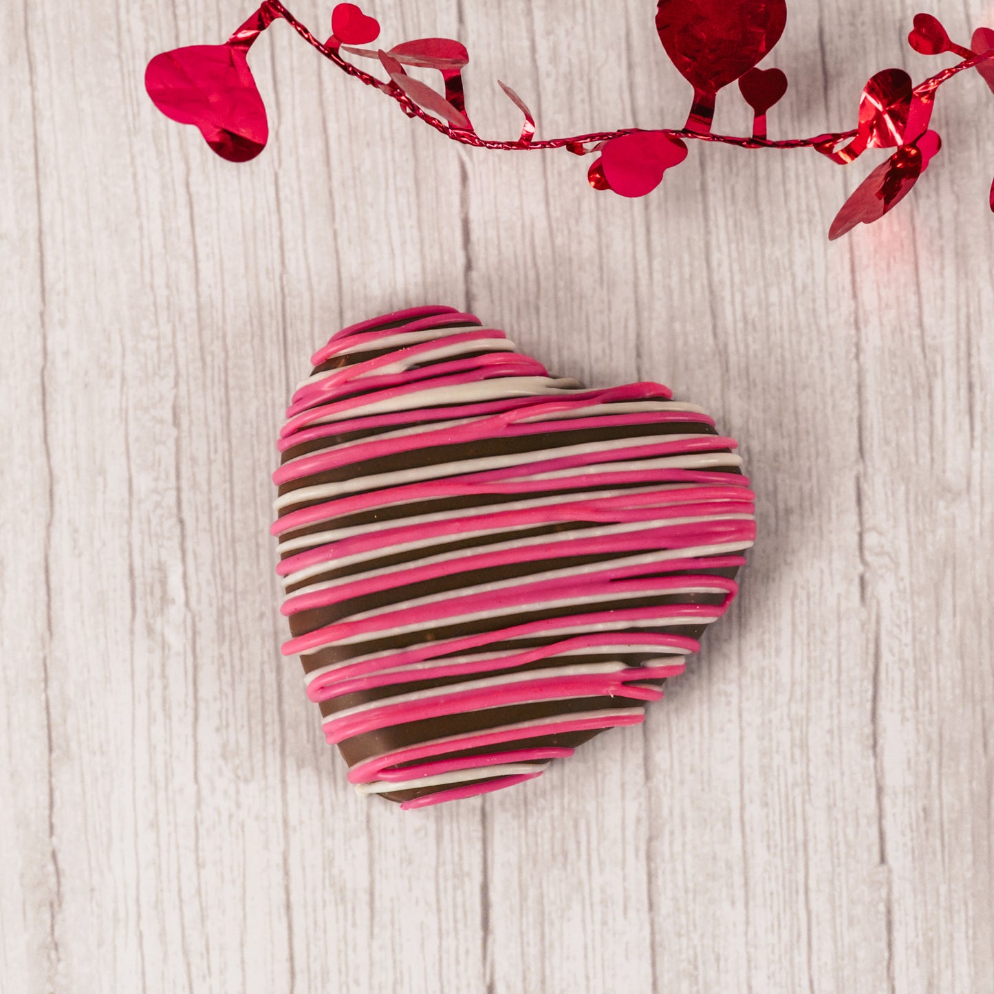 a wonderful marshmallow heart treat dipped in smooth milk chocolate and drizzled with pink and white icing.