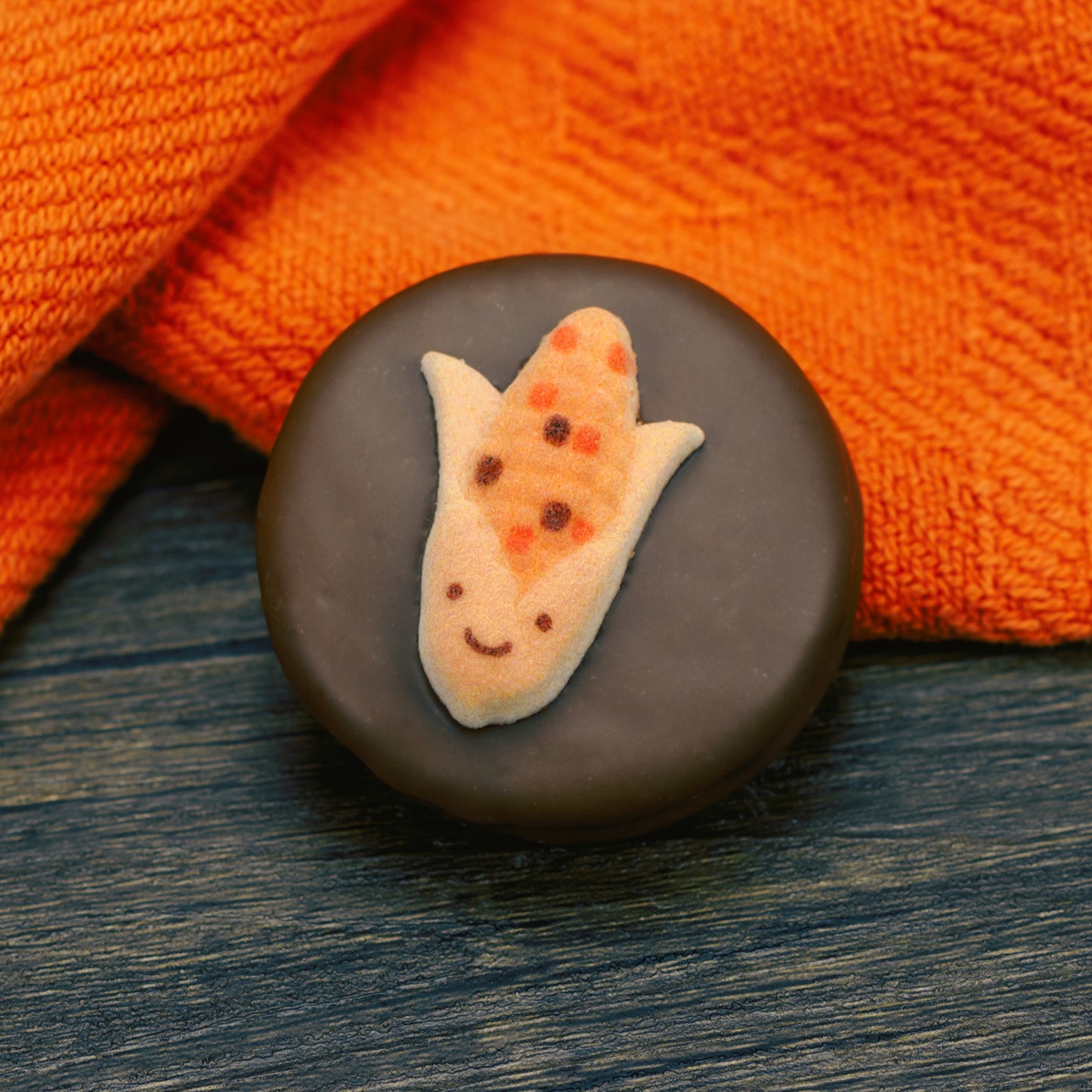 Oreo cookie dipped in milk chocolate with fall corn face decoration on top.