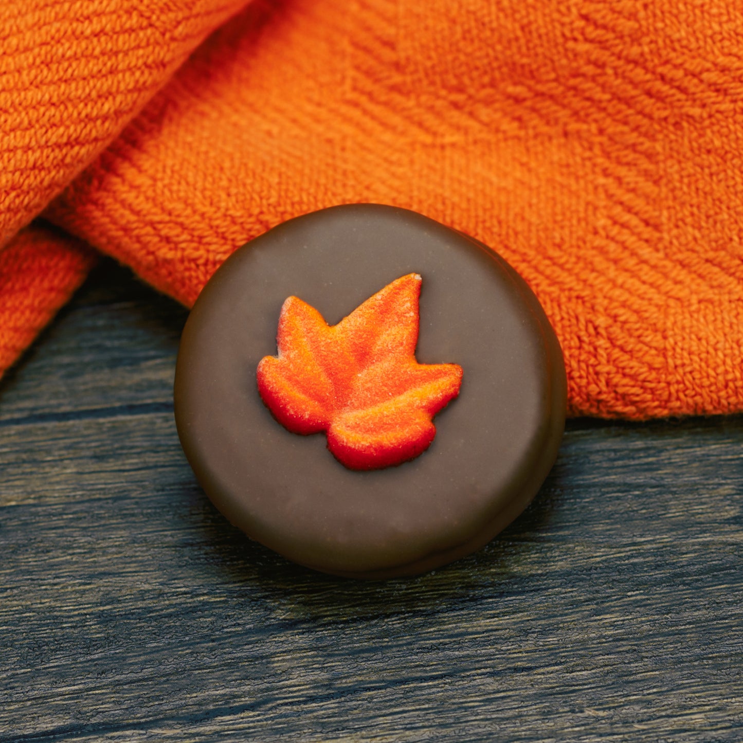 Oreo cookie dipped in milk chocolate with fall leaf decoration on top.
