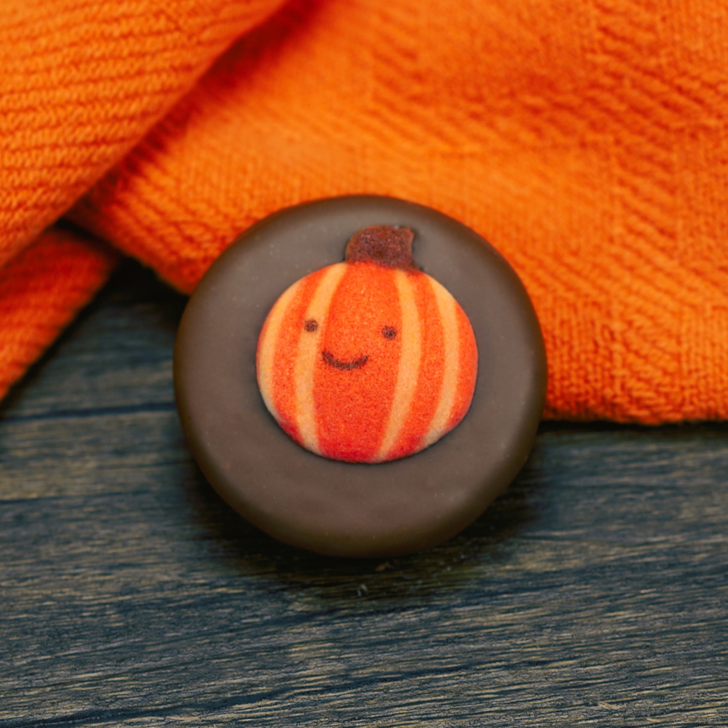 Oreo cookie dipped in milk chocolate with fall pumpkin face decoration on top.