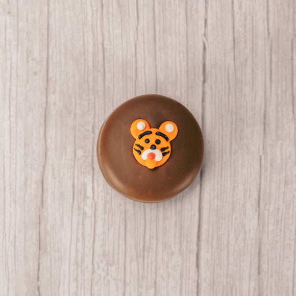 an oreo cookie covered in milk chocolate with a tiger face sugar decoration on top.