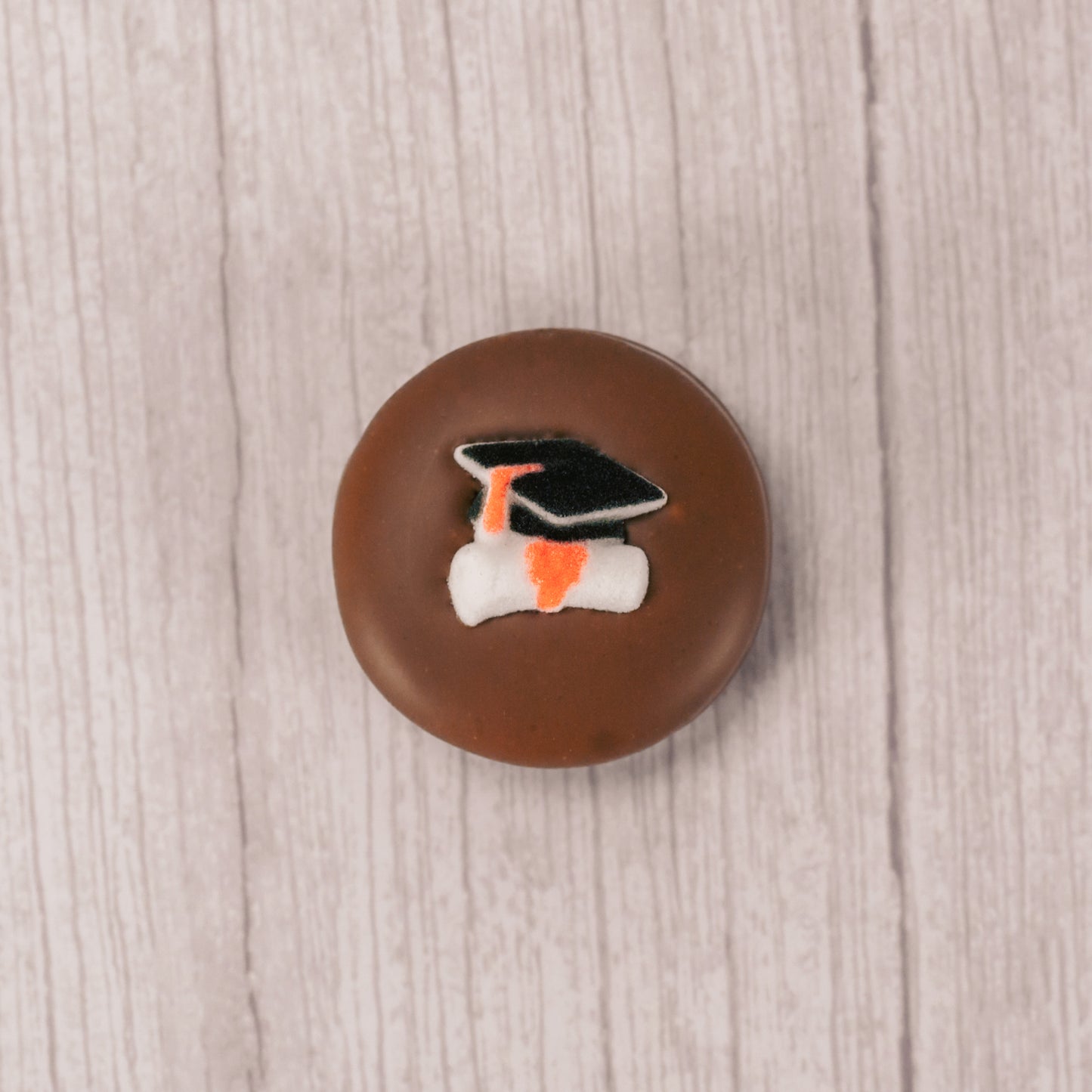 milk chocolate covered Oreo with a sugar grad cap and scroll decoration on top