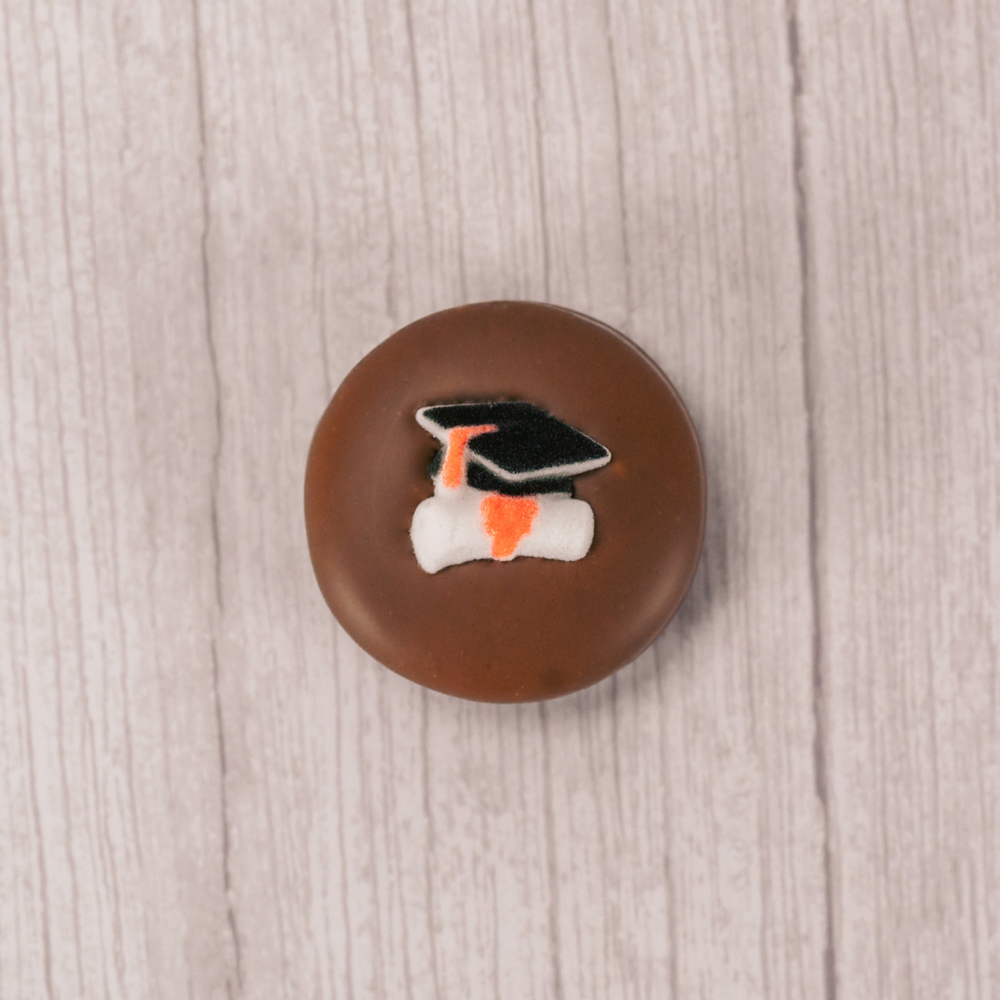 milk chocolate covered Oreo with a sugar grad cap and scroll decoration on top