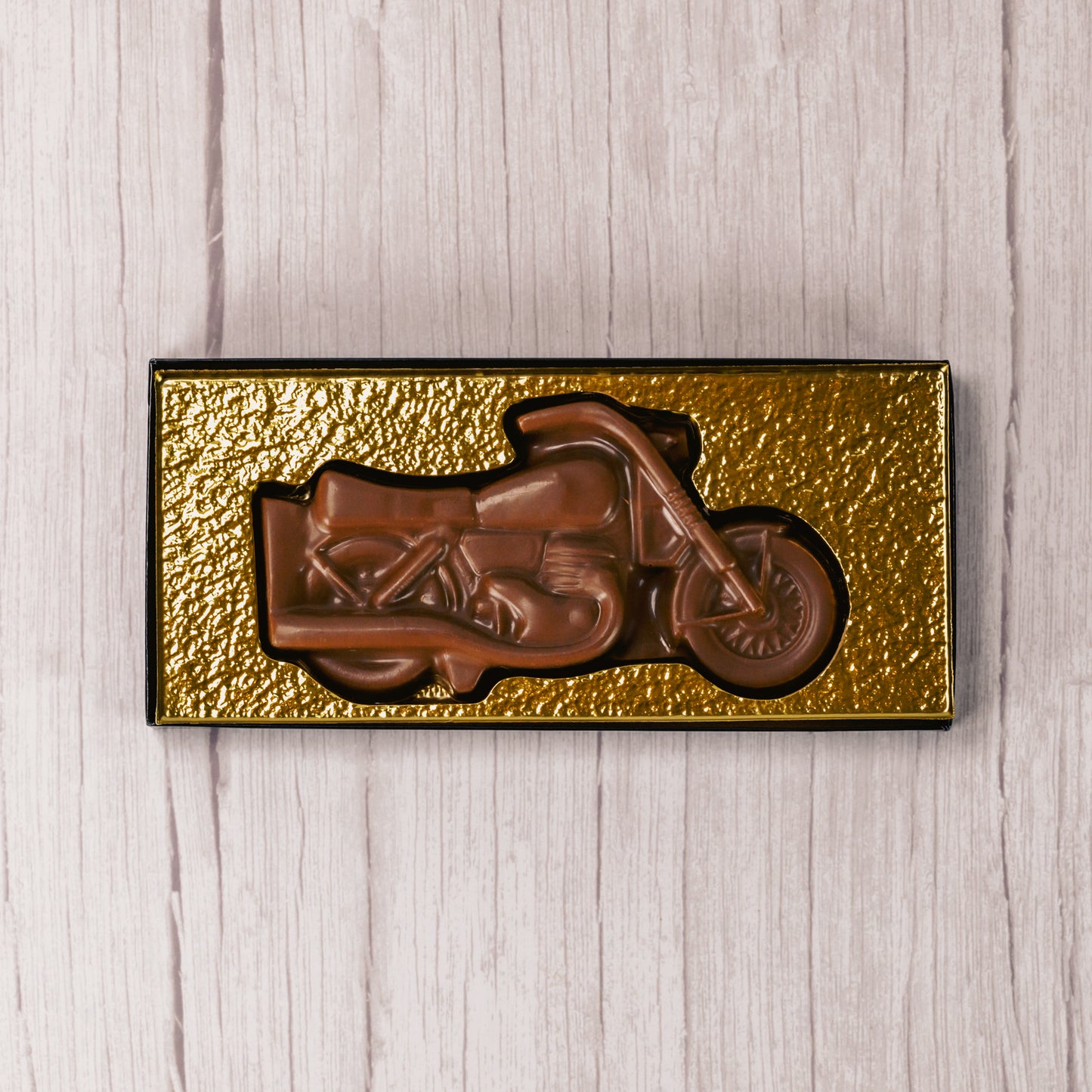 A motorcycle made of smooth milk chocolate is placed in a box with a clear lid, ready to be given as a gift to all of your motorcycle enthusiasts!