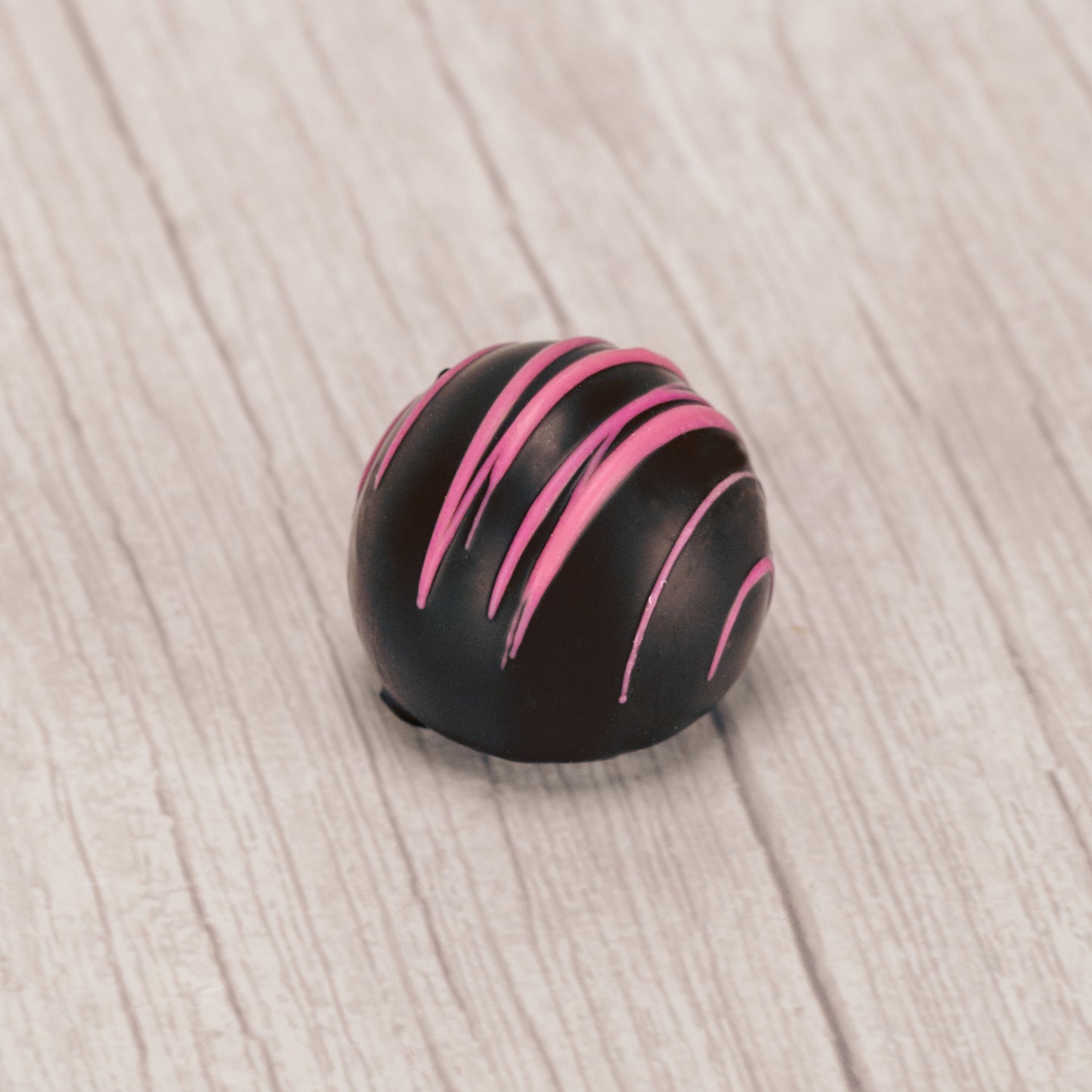 dark chocolate raspberry truffle with pink drizzle icing on top