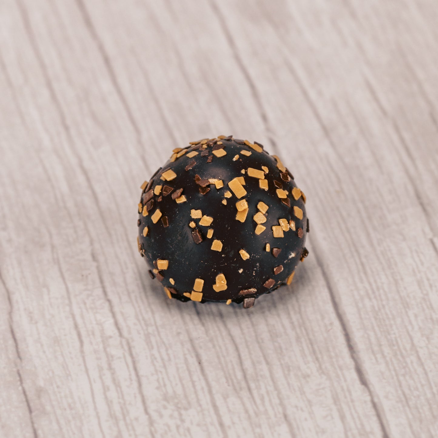 dark chocolate tiramisu truffle with brown and tan sprinkles on top