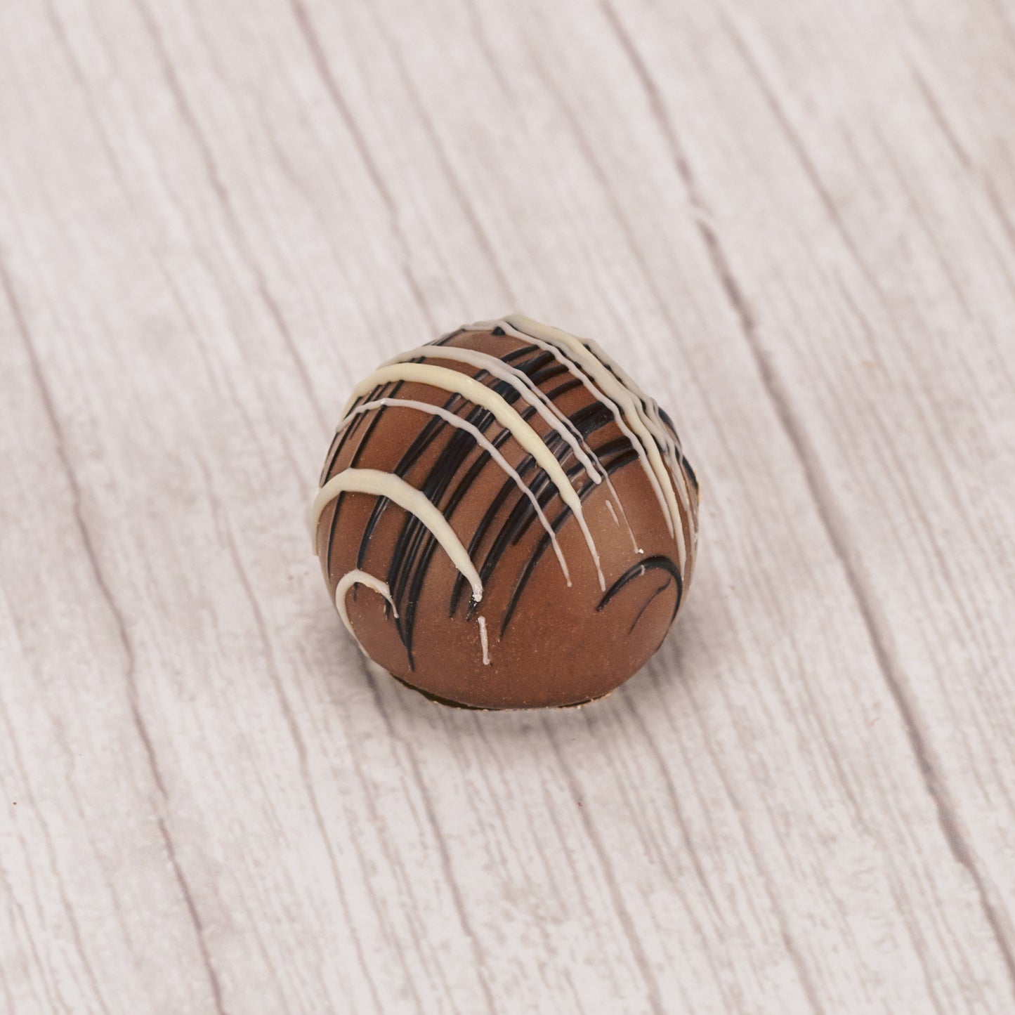 milk chocolate caramel truffle with white and dark chocolate drizzle icing on top