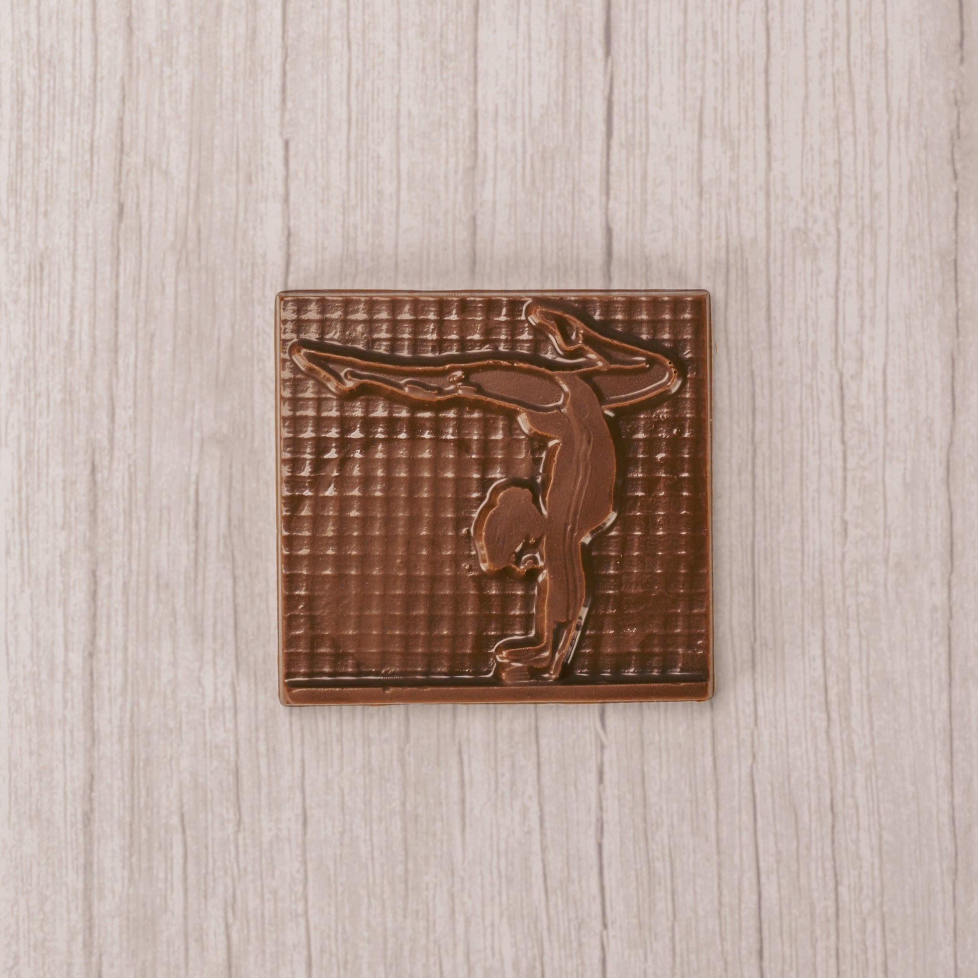 A square plaque of a gymnast in smooth milk chocolate.