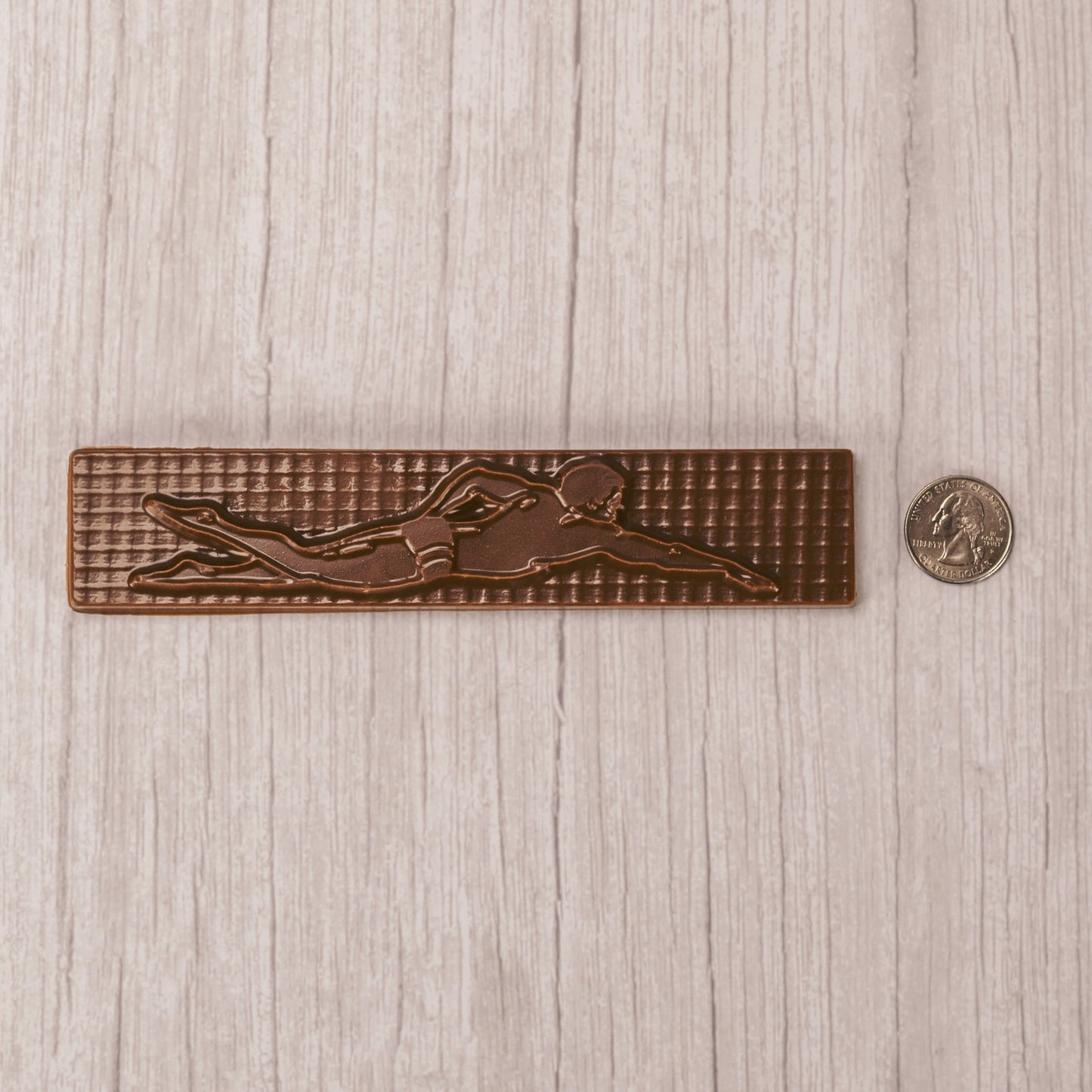 a long plaque of a swimmer in mid stroke in smooth milk chocolate.