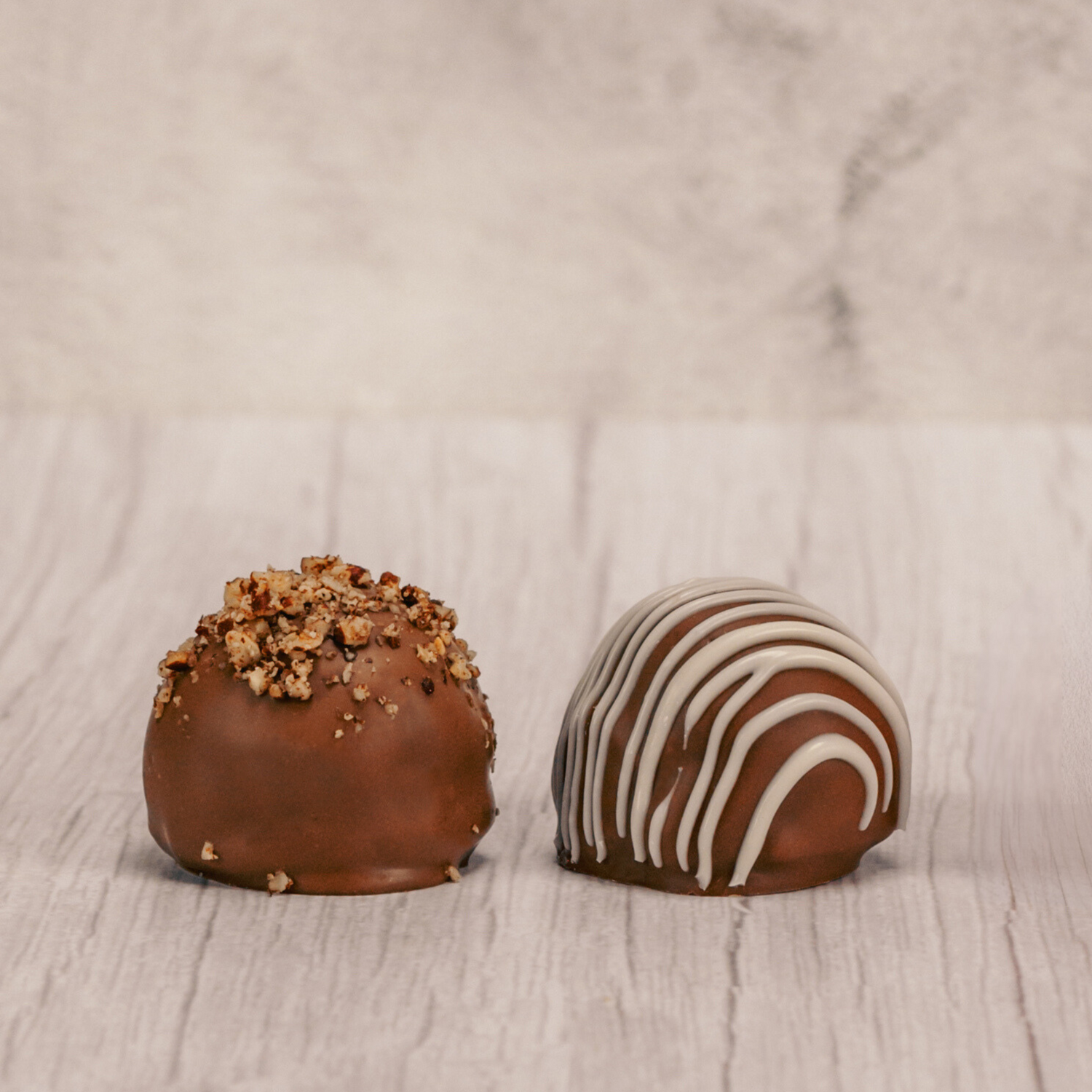 Crushed pecans being sprinkled on chocolate truffles.