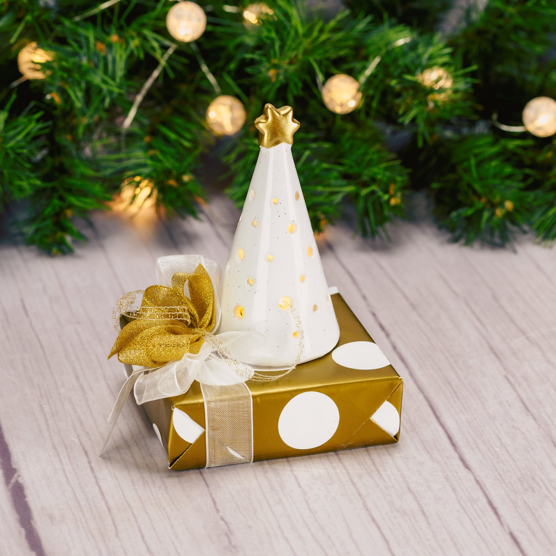 A mini white ceramic tree with built-in illumination, gracefully positioned atop a Sampler box of Assorted Chocolates. 
