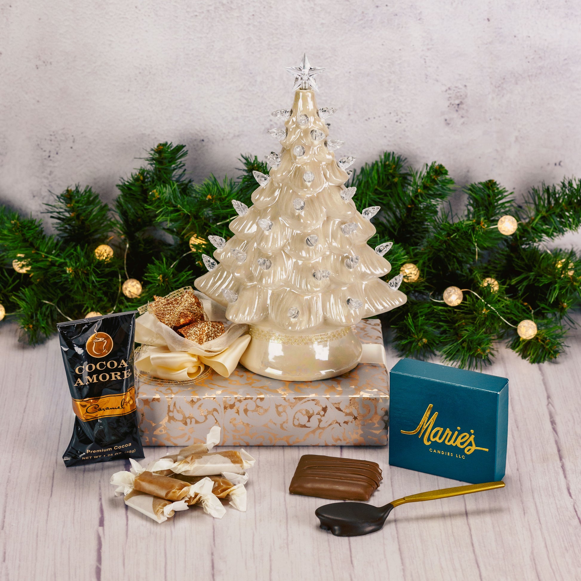 An 8 inch gold pearlescent lighted ceramic tree sits atop a box wrapped in gold filagree paper and tied with a gorgeous handmade bow.
