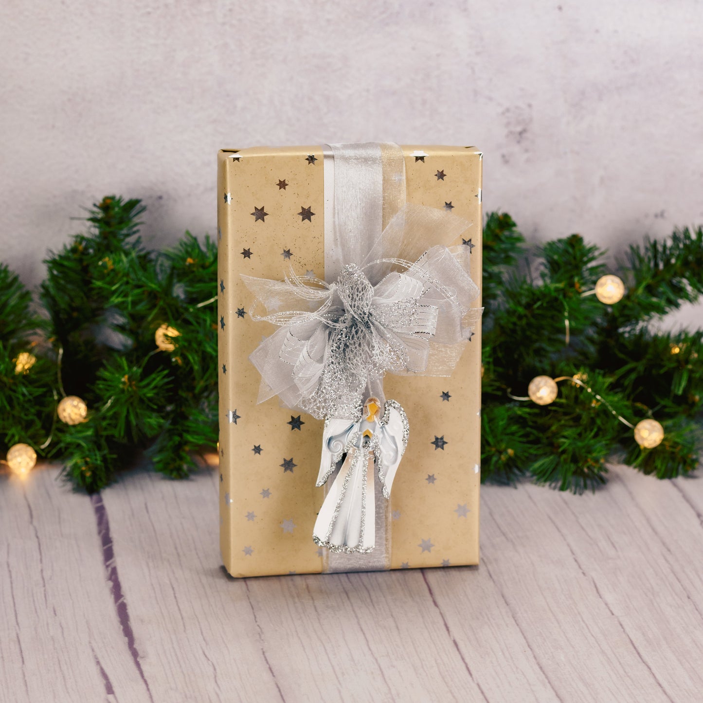 a one pound box of assorted chocolates is wrapped in gold or silver and topped with a matching springy metal angel ornament