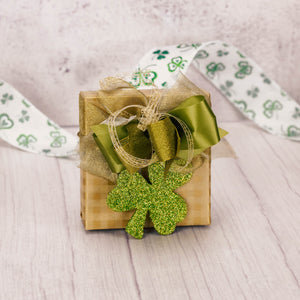 a sampler box of assorted chocolates topped with a glittery green shamrock ornament