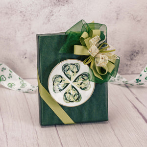 a half pound box of assorted chocolates wrapped in green and topped with a shamrock trinket dish