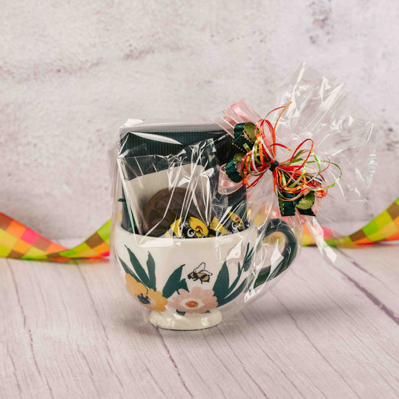 a mug with bees and blossoms is filled with some sweet candy treats