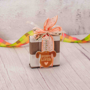 a sampler box of assorted chocolates is topped with an acrylic puppy keychain that reads 'puppy lover'