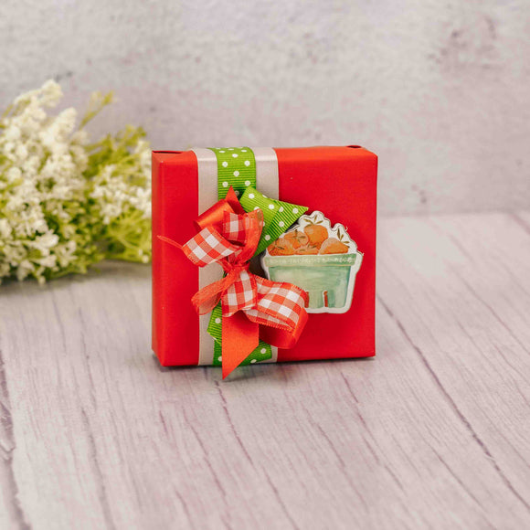  A petite wooden strawberry magnet sits atop a box of our Assorted Chocolates.