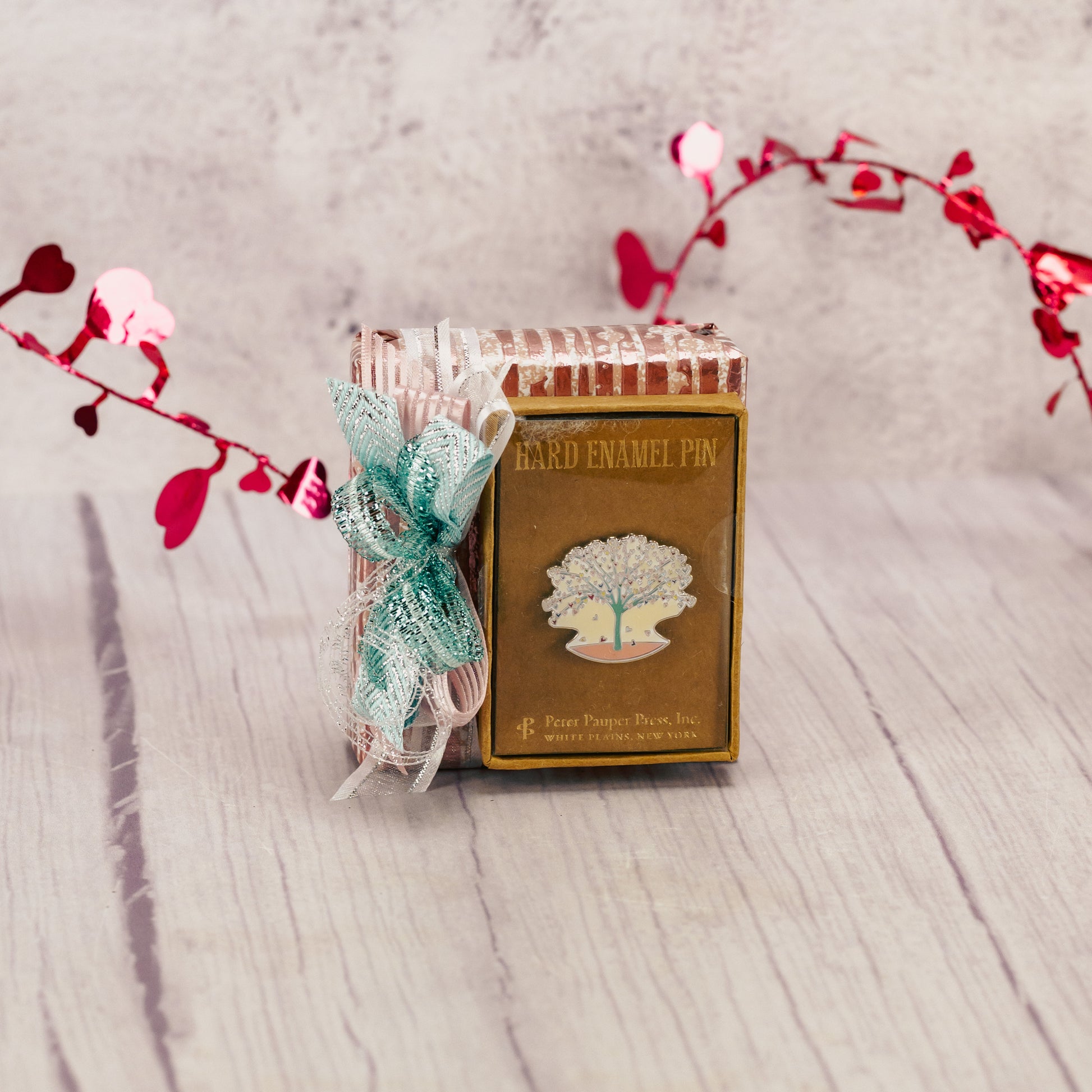 a sampler box topped with a tree of hearts enamel pin. 