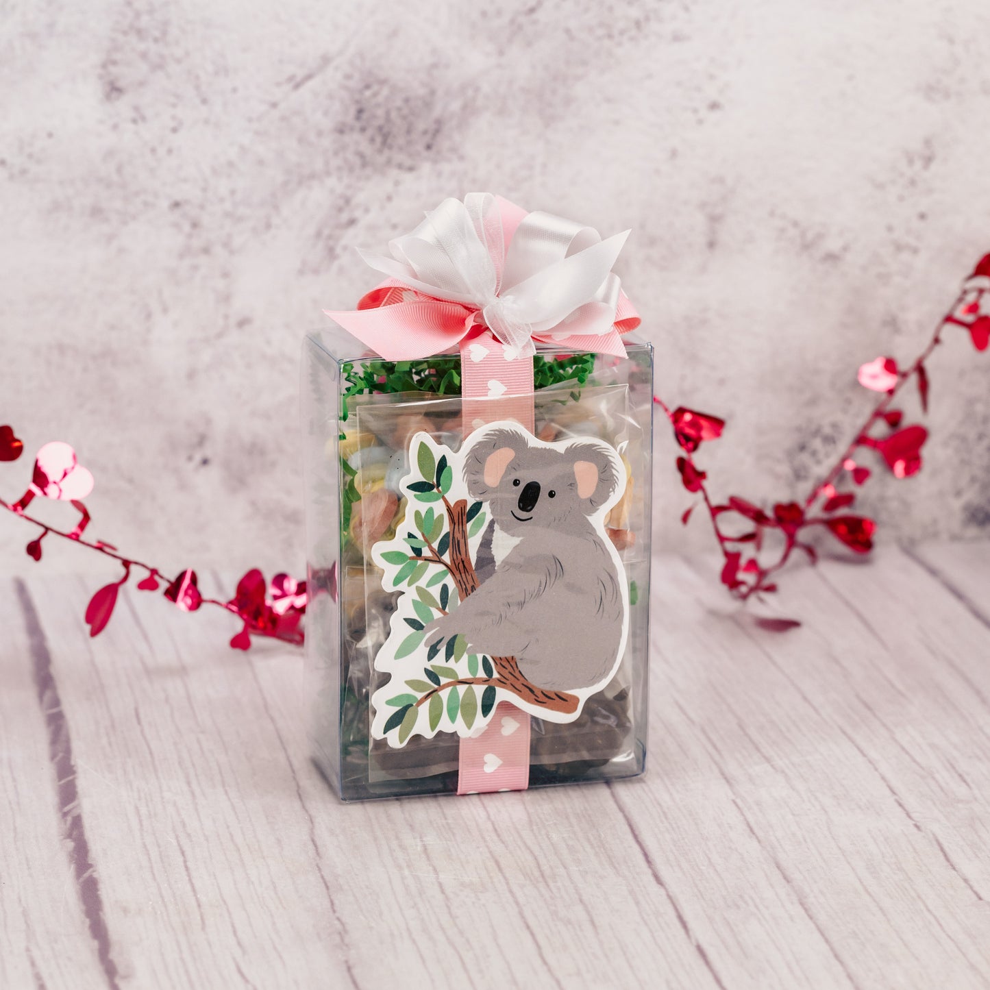 a decorative wooden koala is packaged with some sweet treats.
