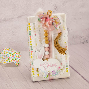 a one pound box of assorted chocolates is wrapped and topped with a wooden bunny with bead garland that reads 'hello spring'