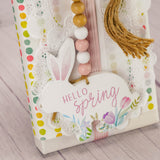 a one pound box of assorted chocolates is wrapped and topped with a wooden bunny with bead garland that reads 'hello spring'