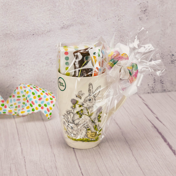 a tall mug with bunnies and clover is filled with some Easter treats