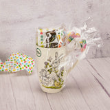 a tall mug with bunnies and clover is filled with some Easter treats