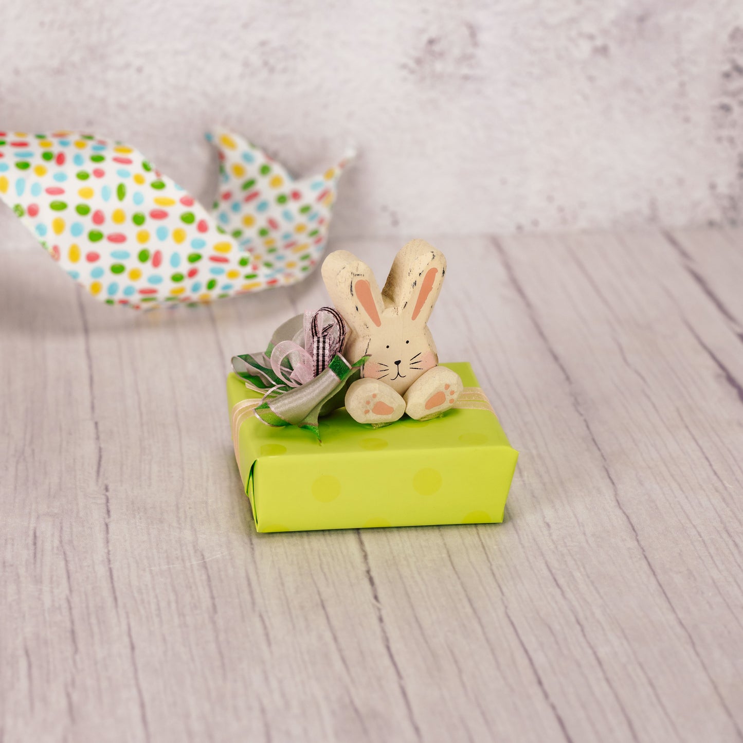 a sampler box of assorted chocolates is wrapped and topped with a wooden chunky bunny sitter
