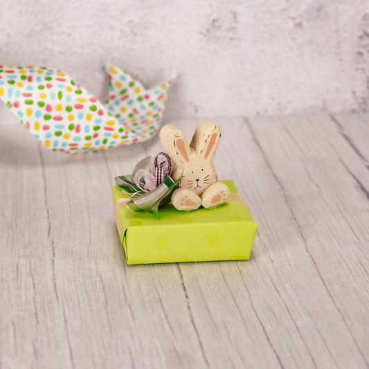 a sampler box of assorted chocolates is wrapped and topped with a wooden chunky bunny sitter
