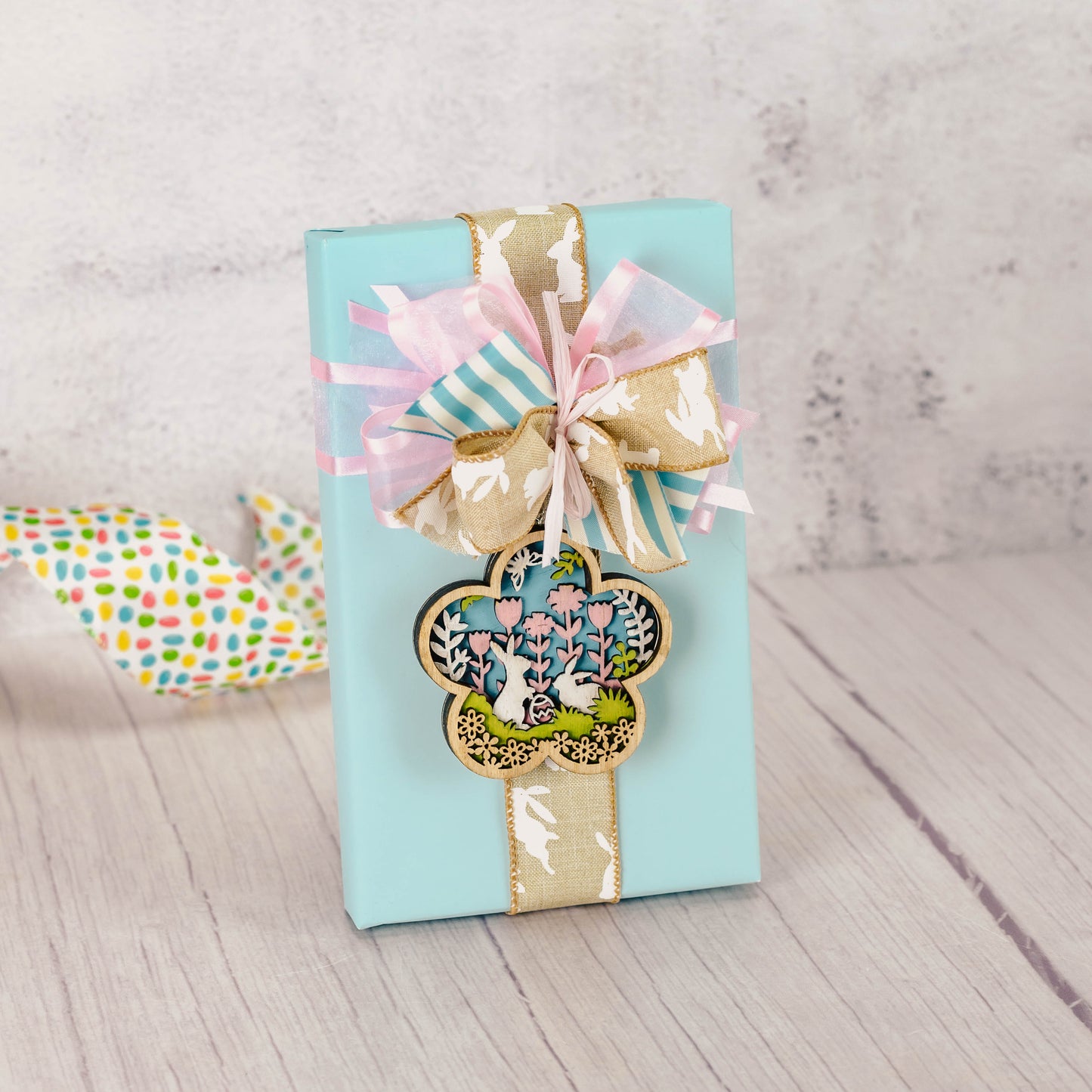 a pound box of assorted chocolates is wrapped and tied with a wooden bunny ornament/magnet