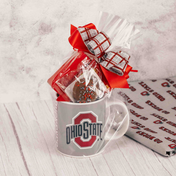 Impress the Buckeye fan in your life with this oversized Block O logo mug that features scarlet on one side and gray on the other. Packaged in a clear bag and tied with a festive handmade bow, we filled it with some of our indulgent candy like:  Scarlet & Gray Oreo  Cherry Jelly Belly Sports Beans  2 oz. Foil Footballs  Sampler 