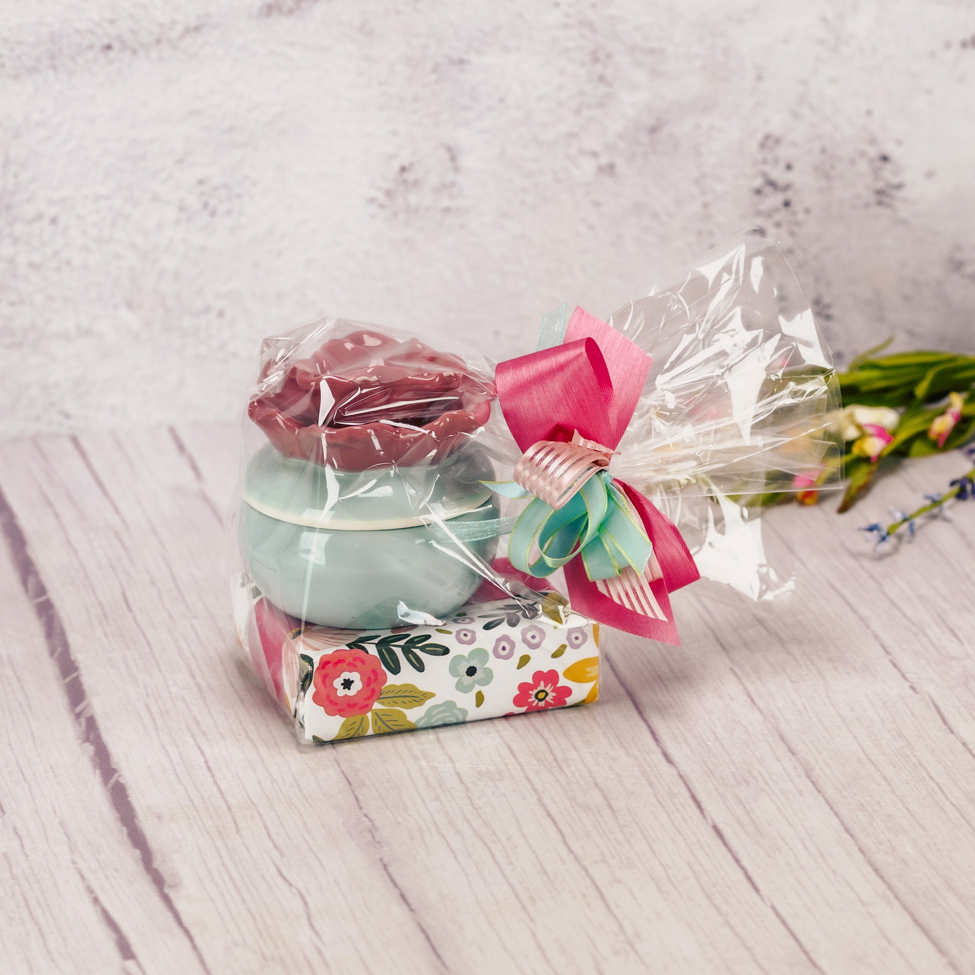  A ceramic teal trinket dish with a rose colored flower lid is packaged with some sweet treats 