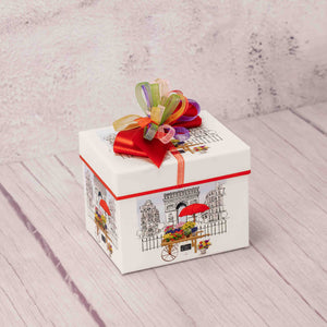 a small gift box with a Paris city scene on each side is filled with scrumptious treats