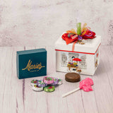 a small gift box with a Paris city scene on each side is filled with scrumptious treats