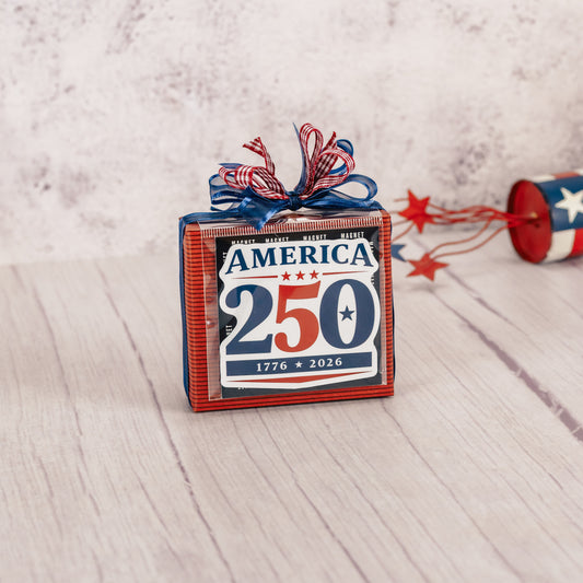 a sampler box of assorted chocolates is wrapped and topped with a magnet that reads 'American 250 - 1776-2026'