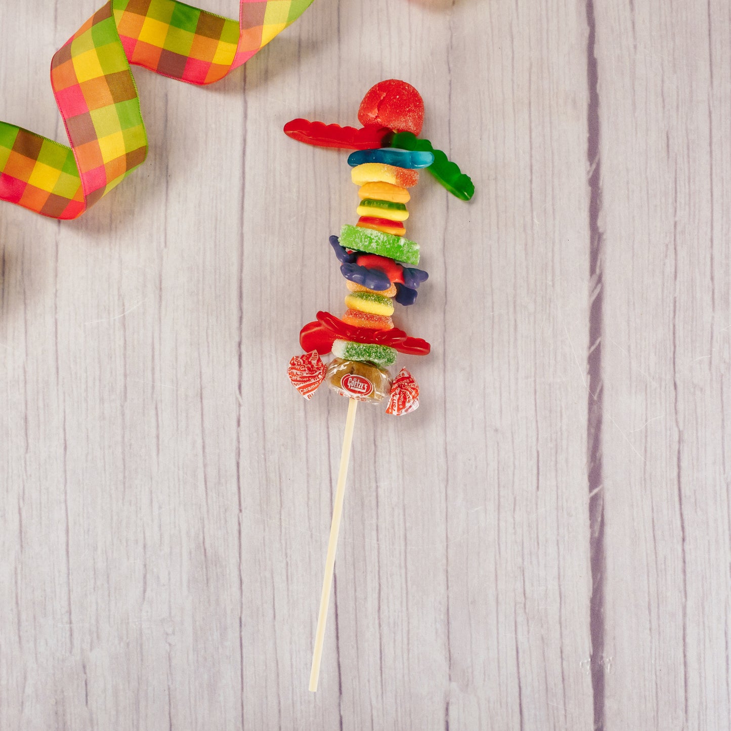 a kebob of assorted gummi pieces like: fruit slices, frogs, worms, cherries and more!