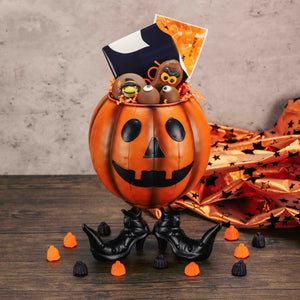 a metal jack-o-lantern pumpkin (with feet) candy bowl  is filled with delicious treats for your Halloween events