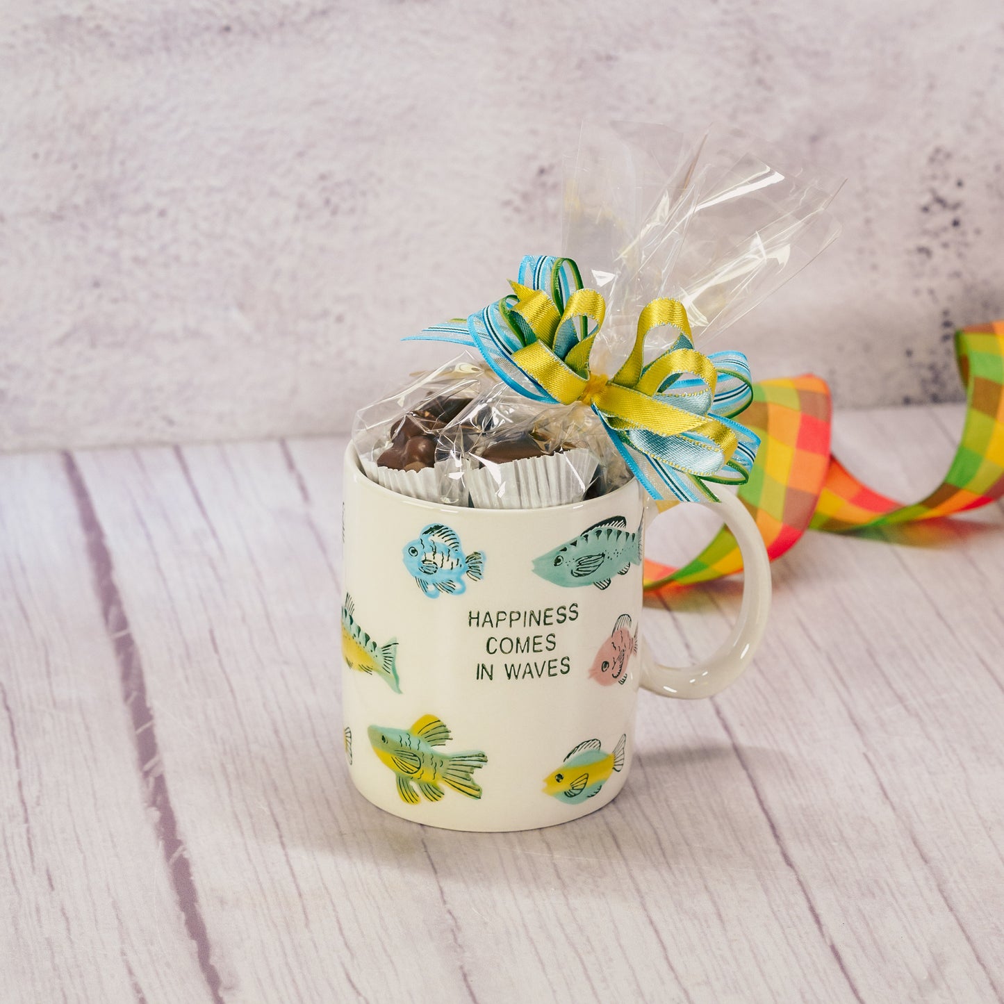 a mug that reads 'happiness comes in waves' with fish all over is filled with a half pound of our assorted milk assorted chocolates