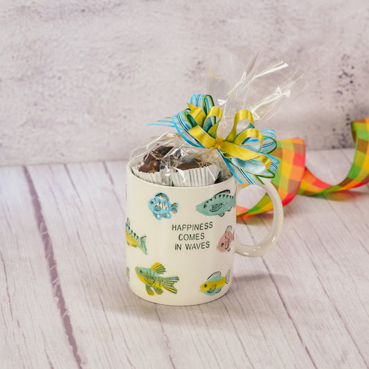 a mug that reads 'happiness comes in waves' with fish all over is filled with a half pound of our assorted milk assorted chocolates