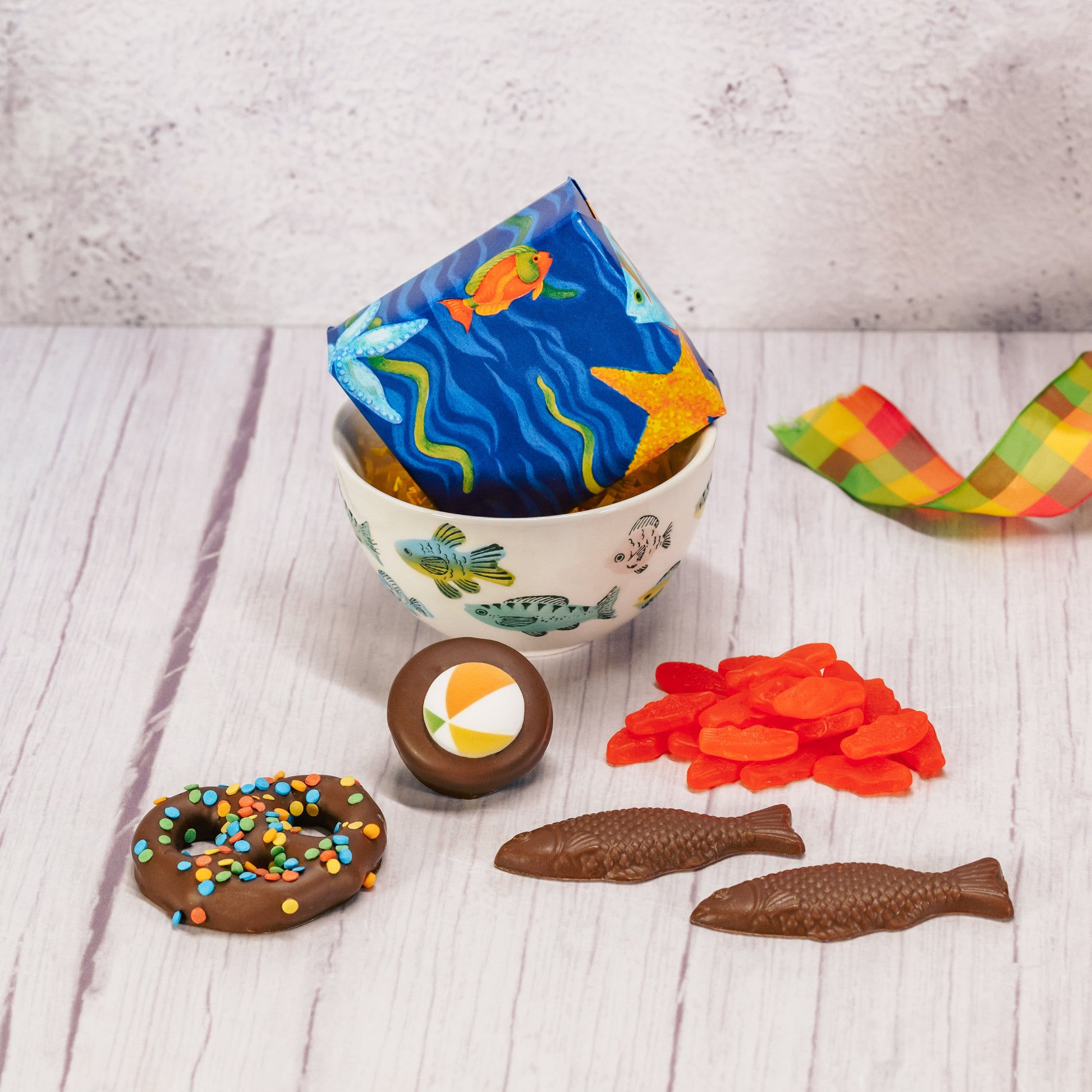 a small snack bowl or ice cream bowl with colorful fish all over is filled with sweet summer treats