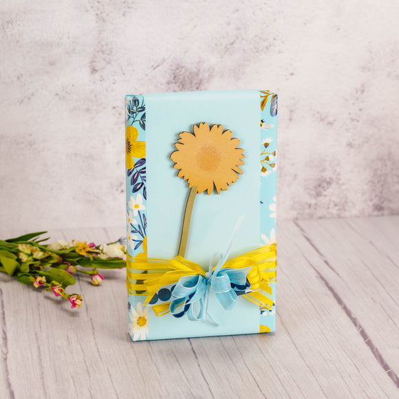 a one pound box of assorted chocolates is wrapped and topped with a decorative wooden daisy cut out stem