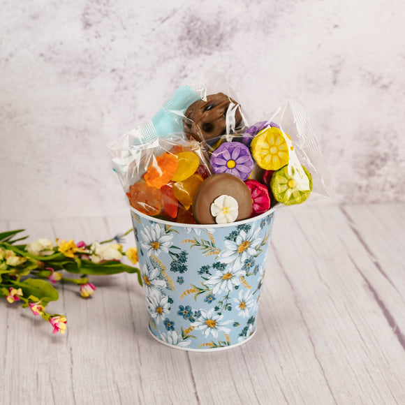 a small metal daisy bucket is filled with sweet treats